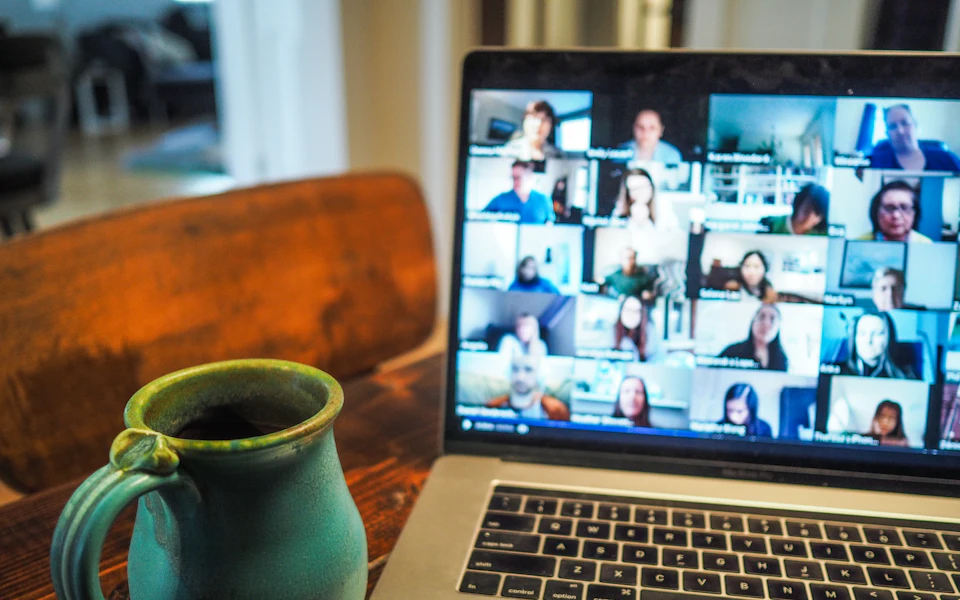 Laptop screen showing a video meeting with many participants