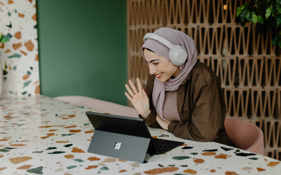Woman wearing headphones listening and smiling at her laptop